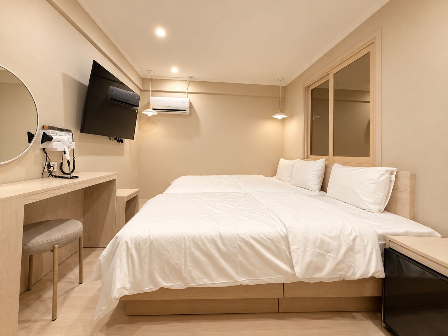 A hotel room with a bed, a desk with a hairdryer, a flat-screen TV, and a large mirror.