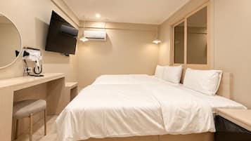 Habitación de hotel con cama, escritorio con secador de pelo, televisor de pantalla plana y un espejo grande.