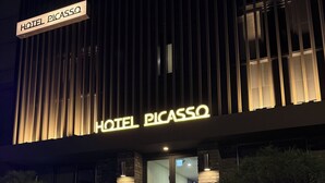 Ein Hotel Eingang mit modernem Design, mit einer auffälligen, beleuchteten Signage, auf der 'HOTEL PICASSO' steht.
