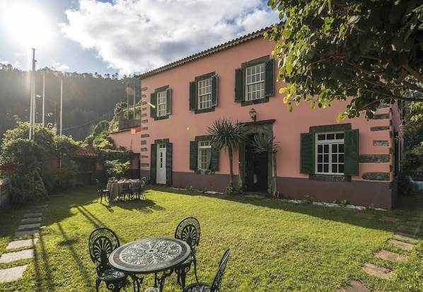 A pink building with a garden patio, a dining table, and chairs.
