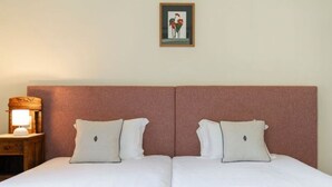 Een tweepersoonsbed met twee kussens en een nachtkastje met een lamp.