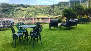 Een terras met tuinmeubilair, een ronde tafel en stoelen.