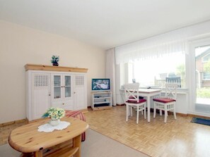 A room with a wooden floor, white furniture, a television, and a window with curtains. - 8 at Konigstr. 5, Atlantic Court (Wyk auf Foehr)