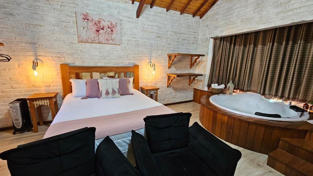 A bedroom with a large bed, a wooden headboard, a bedside table, a nightstand, a black chair, a wooden bench, a wooden shelf, a wall-mounted light fixture, a painting, and a bathtub.