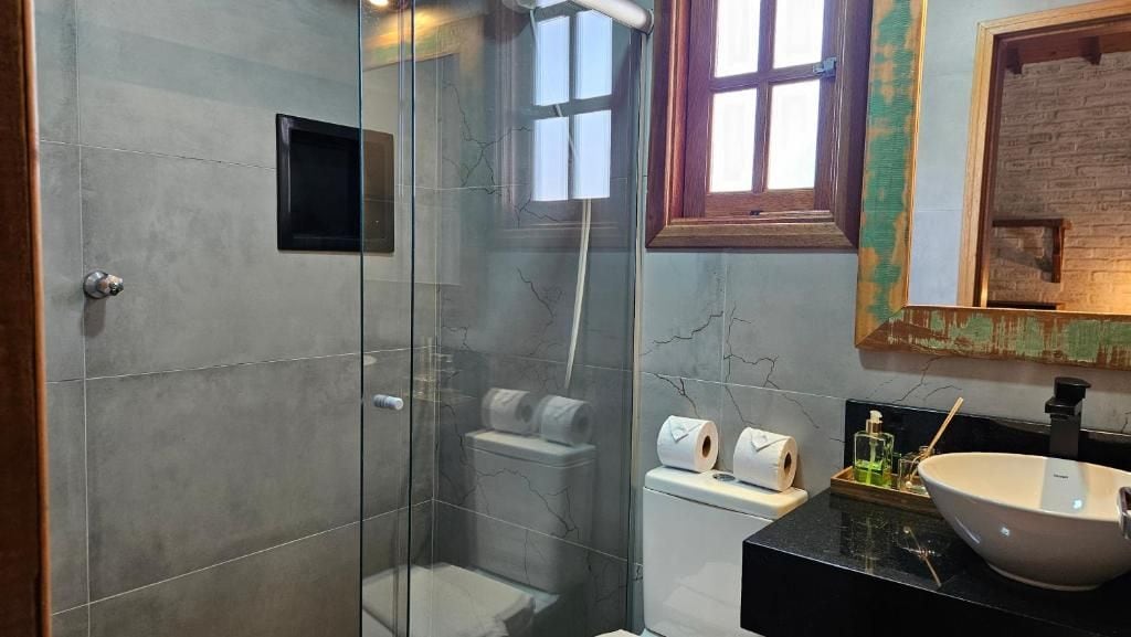 A bathroom with a glass-enclosed shower, a toilet, and a sink with a large bowl.