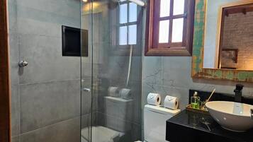 A bathroom with a glass-enclosed shower, a toilet, and a sink with a large bowl.