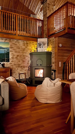 Un intérieur de chalet chaleureux avec une cheminée, des murs en bois et un espace aménagé en mezzanine.
