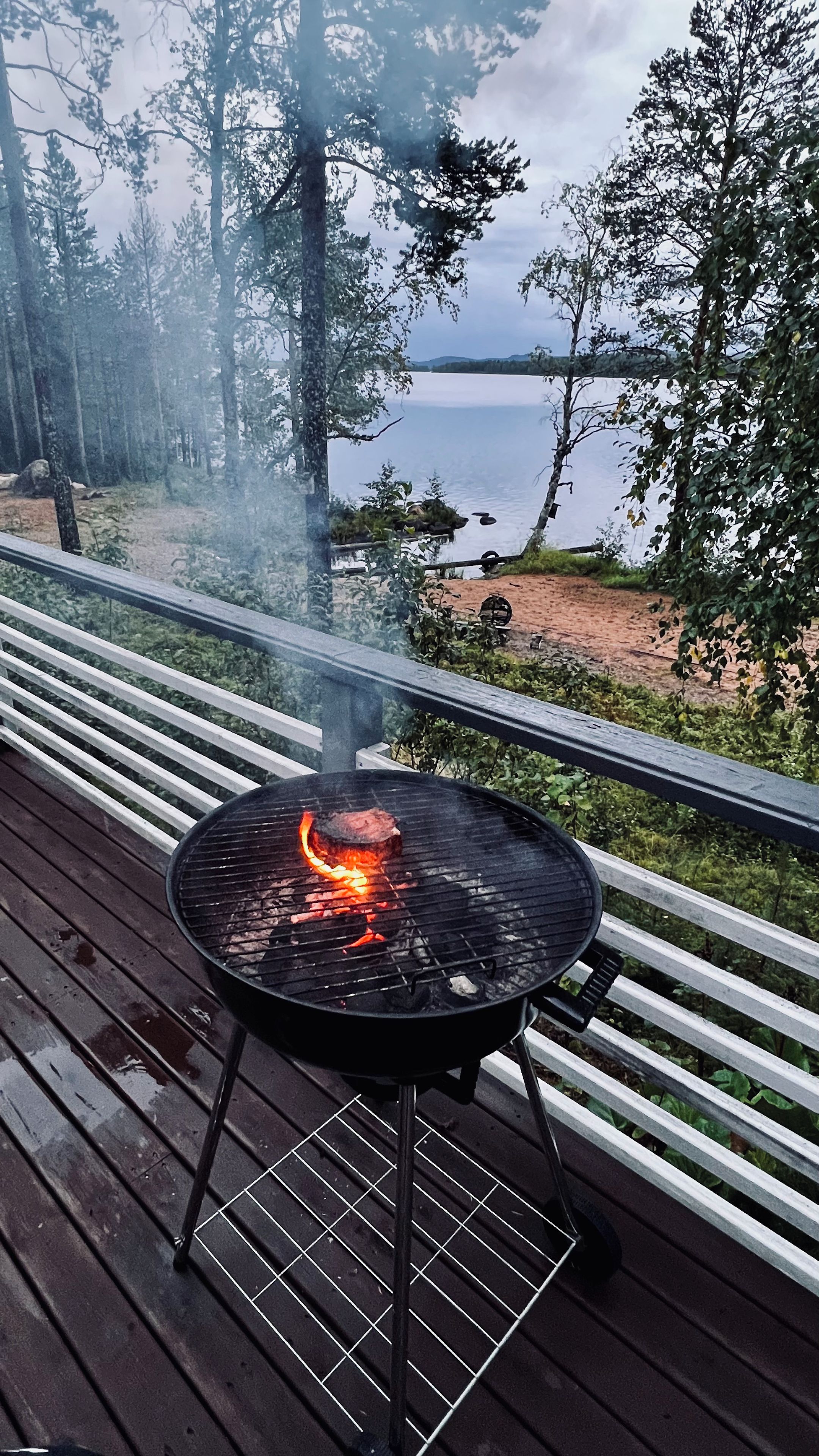 En grill på en træterrasse med udsigt over et sø.