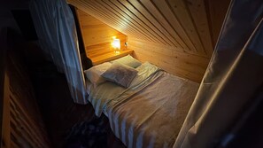Une pièce confortable avec un lit, une table de chevet dotée d’une lampe et des murs en bois.