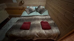 A bed with a grey blanket, two pillows, and two red towels. - Vrbo Property (pello)