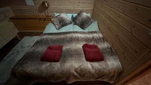 A bed with a grey blanket, two pillows, and two red towels. - Vrbo Property (pello)