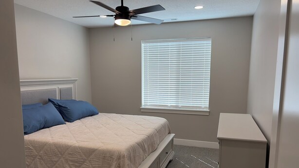 A bedroom with a bed, a ceiling fan, a window with blinds, and a nightstand. - New 3-bedroom house with AC in charming Mapleton with covered walk-out patio. (Mapleton)