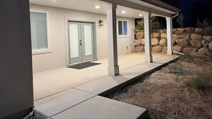 A covered outdoor area with a stone wall and a door with frosted glass panels. - New 3-bedroom house with AC in charming Mapleton with covered walk-out patio. (Mapleton)