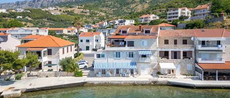 A coastal town with stone buildings, clear waters, and a boat docked at the pier.