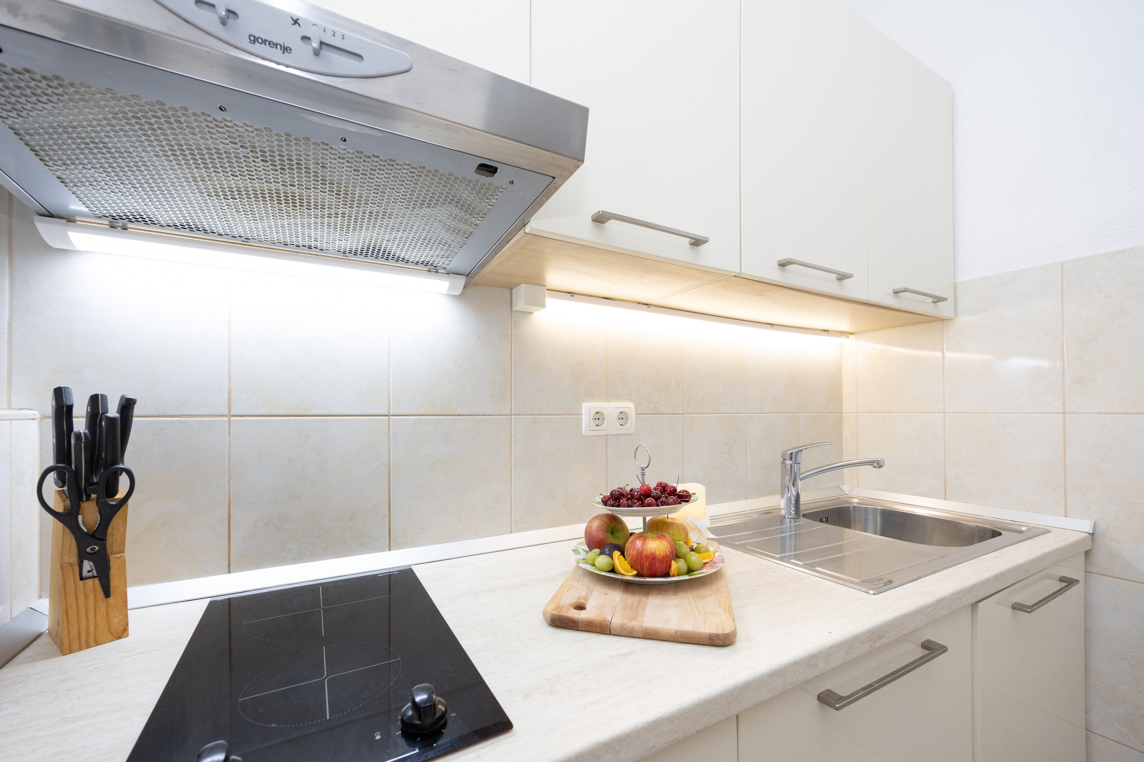 Une cuisine moderne équipée d’une cuisinière intégrée, d’un évier et d’un présentoir à fruits.