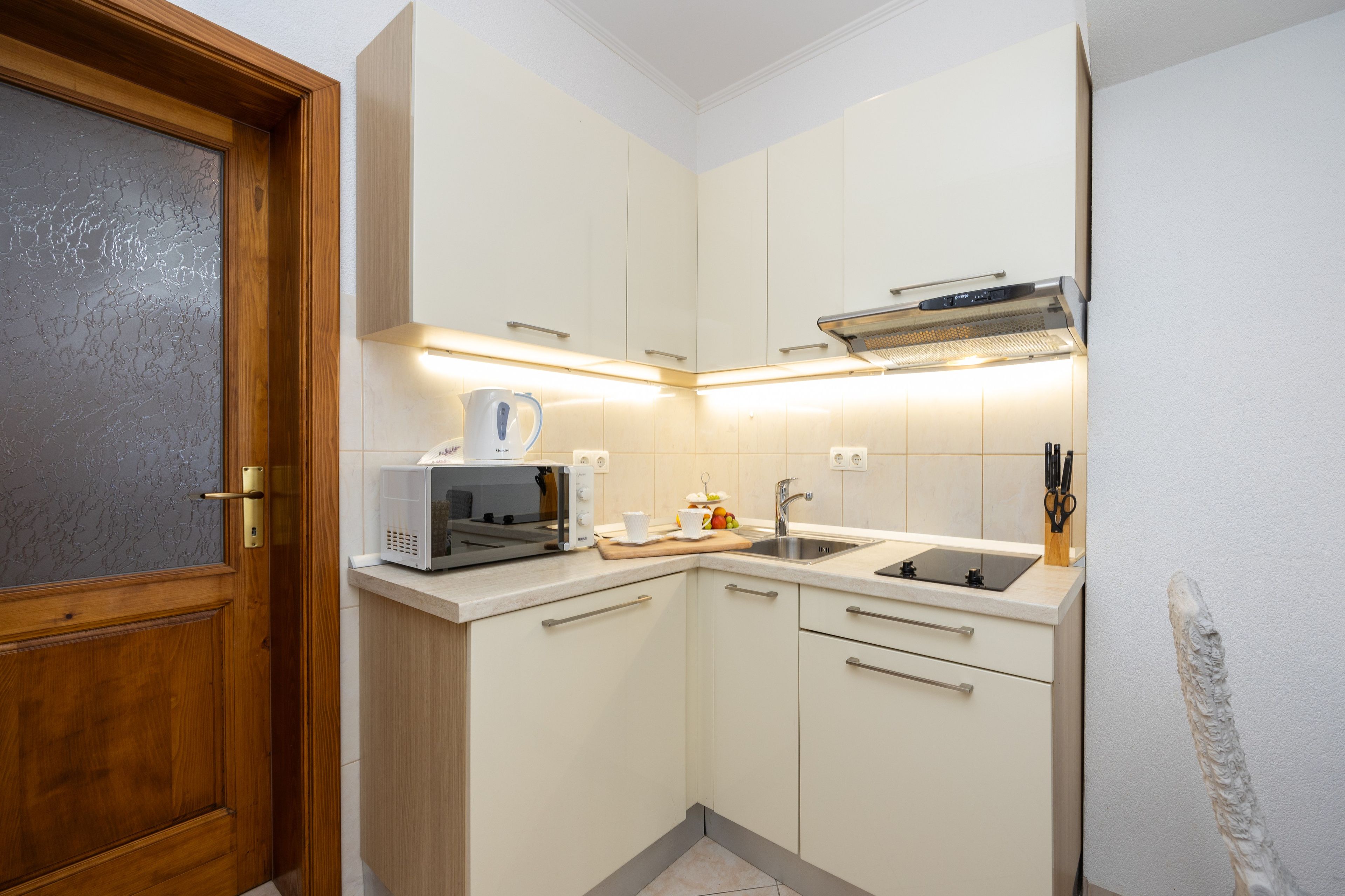 Een functionele keuken met een magnetron, broodrooster, spoelbak en afzuigkap.