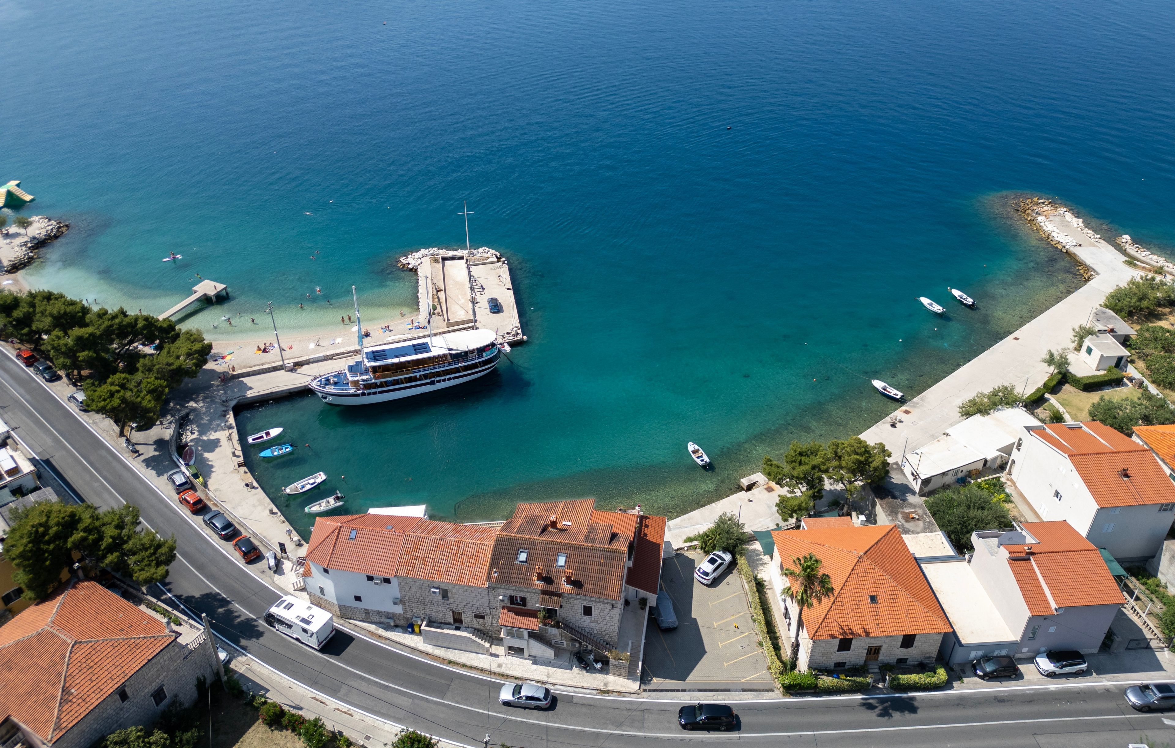 Une ville côtière dotée d’un port de plaisance, de bateaux et de bâtiments aux toits recouverts de tuiles rouges.