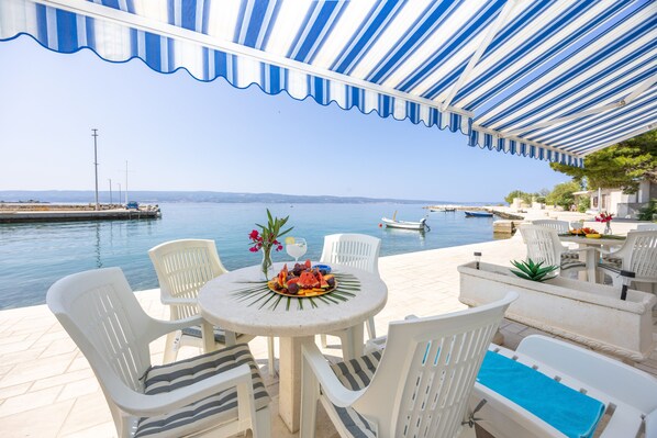 A seaside patio with a table set for dining, overlooking the sea.