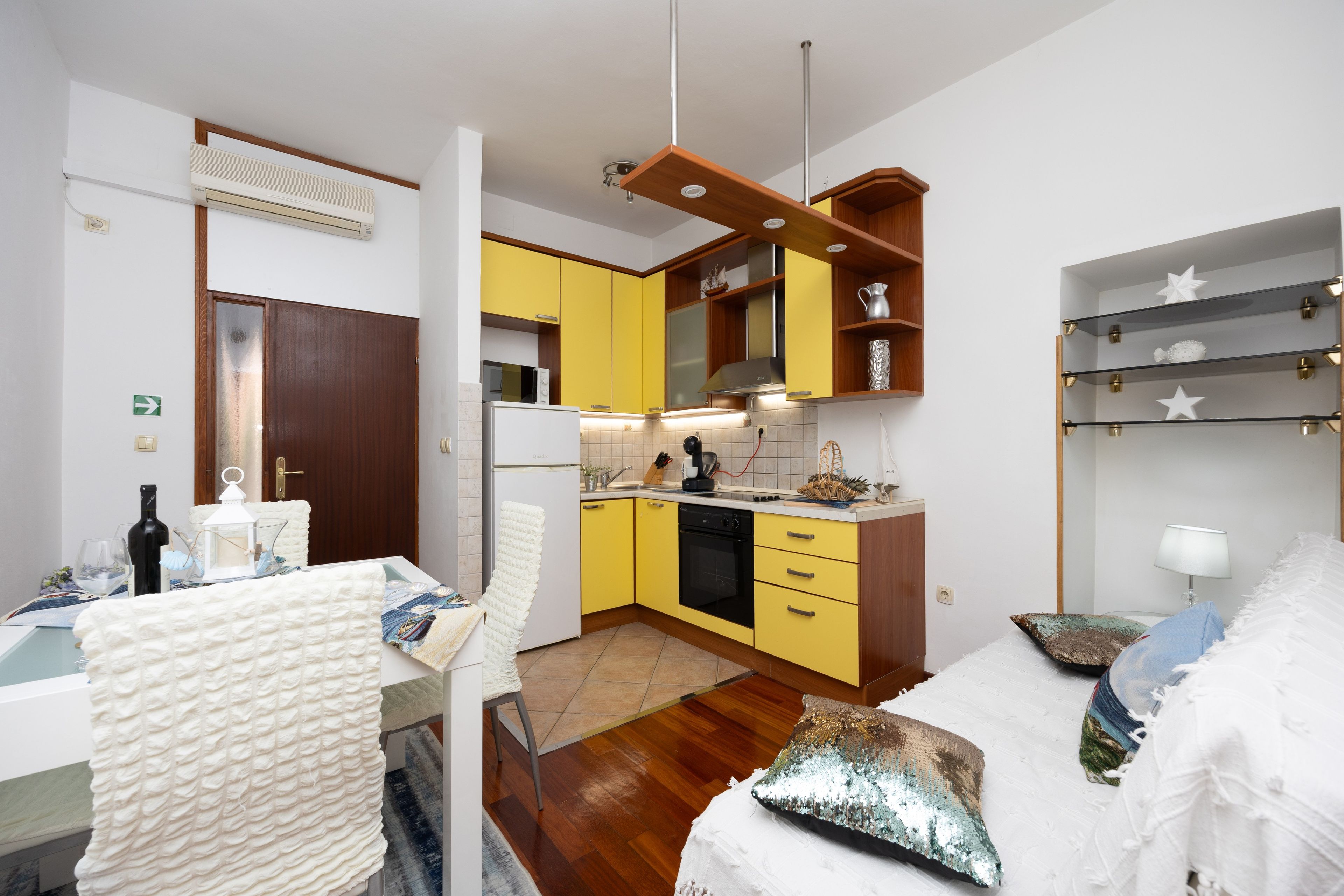 A compact kitchen with yellow cabinets, a white refrigerator, and a wooden ceiling.