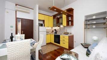 A compact kitchen with yellow cabinets, a white refrigerator, and a wooden ceiling.