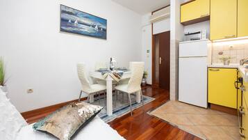 Un comedor con una mesa y sillas, un cuadro en la pared y una cocina con armarios amarillos.