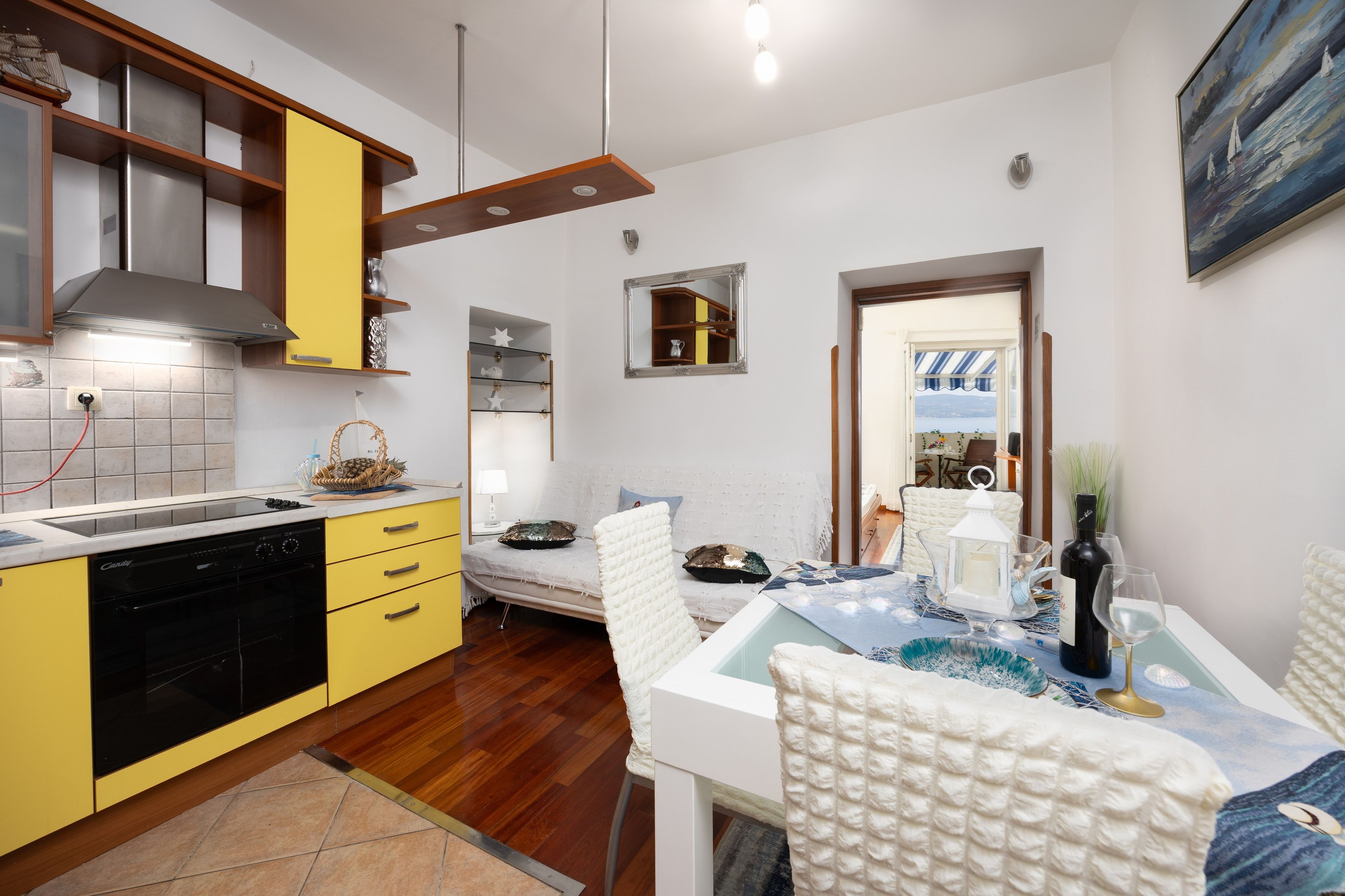 Une cuisine moderne avec des meubles de couleur jaune, un four encastré et un coin repas avec une table dressée pour deux personnes.