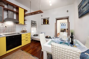 A modern kitchen with yellow cabinets, a built-in oven, and a dining area with a table set for two.