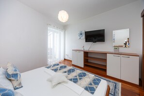 A bedroom with a bed, a TV, a mirror, and a wooden cabinet.