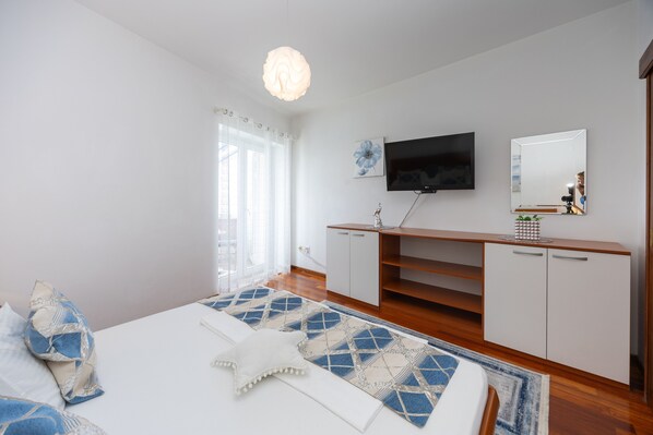 A bedroom with a bed, a TV, a mirror, and a wooden cabinet.