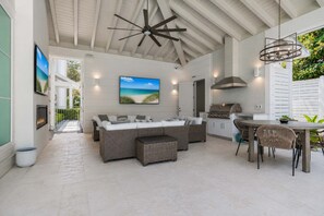 A modern outdoor living area with a sofa, dining table, and grill. - Private Pool, 4 King En-suites + Bunk Room, Outdoor Fireplace & Kitchen (Santa Rosa Beach)