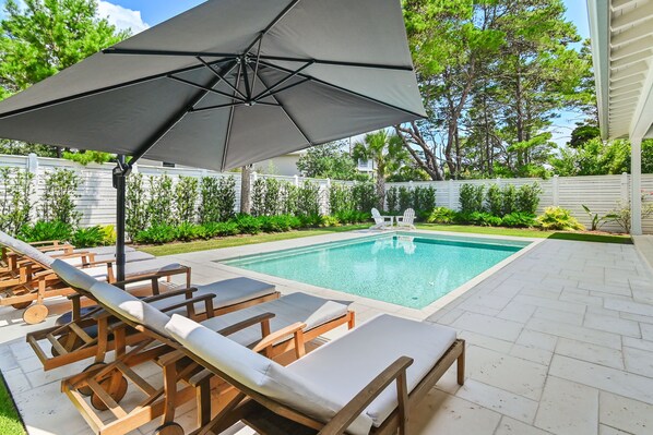 A swimming pool with lounge chairs and an umbrella. - Private Pool, 4 King En-suites + Bunk Room, Outdoor Fireplace & Kitchen (Santa Rosa Beach)