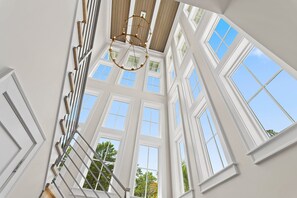 A high-ceilinged room with multiple windows and a central chandelier. - Private Pool, 4 King En-suites + Bunk Room, Outdoor Fireplace & Kitchen (Santa Rosa Beach)