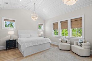 A bedroom with a large bed, two bedside tables, a chair, and a window with a view of greenery. - Private Pool, 4 King En-suites + Bunk Room, Outdoor Fireplace & Kitchen (Santa Rosa Beach)