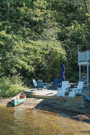 A lakeside deck with outdoor seating and a swing chair. - Lakefront vacation home with hot tub, private sandy beach, and fire pit (Palmer)