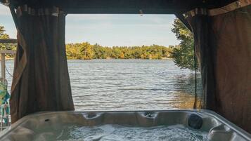 A hot tub with a view of a lake and trees.