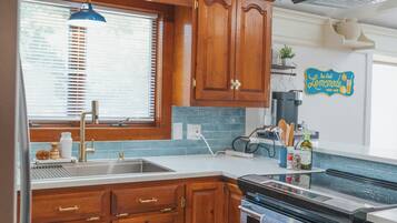 A kitchen with wooden cabinets, a built-in oven, a window with blinds, and a ceiling light fixture.