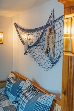 A hammock hanging on a wall, a fish decoration, and a bed with a checkered blanket. - Lakefront vacation home with hot tub, private sandy beach, and fire pit (Palmer)