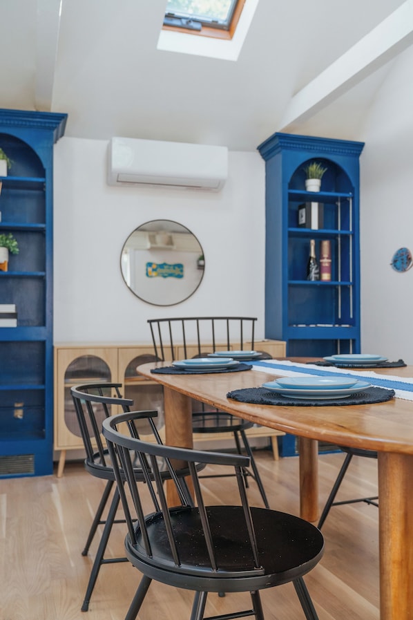 A dining area with a wooden table, black chairs, and blue shelving units.