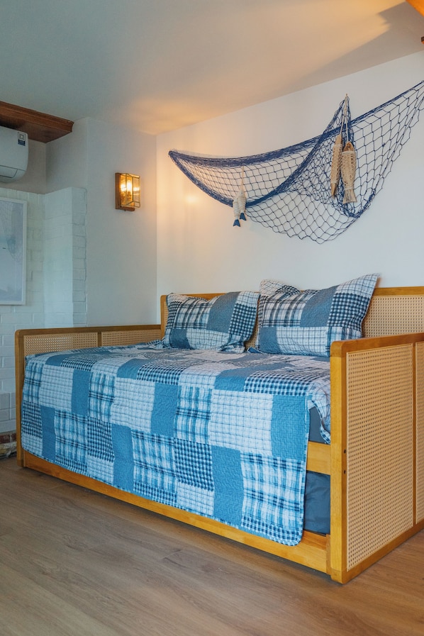 A bed with a blue and white checkered bedspread, wooden headboard, and a hanging net decoration. - Lakefront vacation home with hot tub, private sandy beach, and fire pit (Palmer)