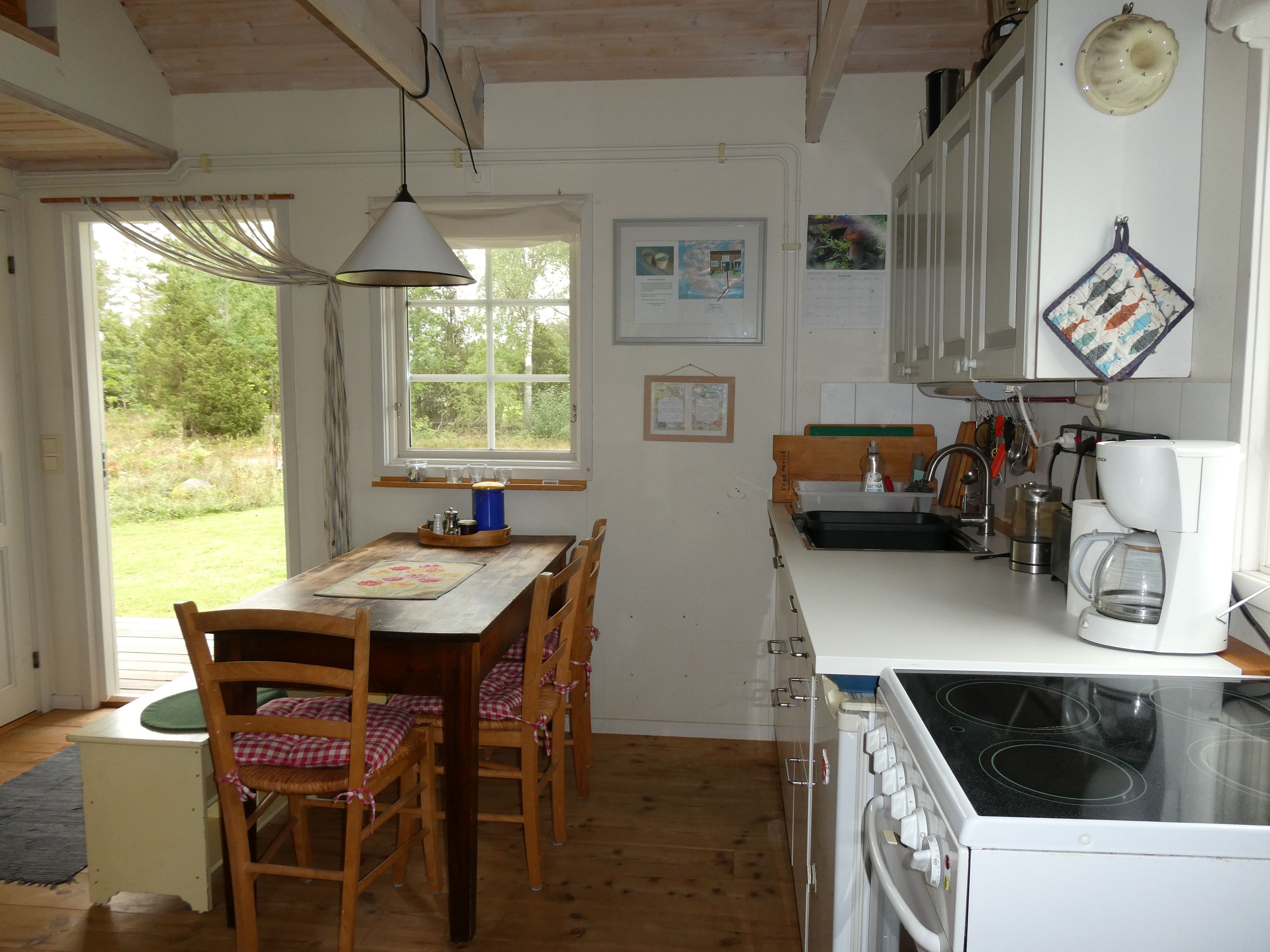 Ett kök med ett matbord, stolar, en kaffebryggare och en spis.