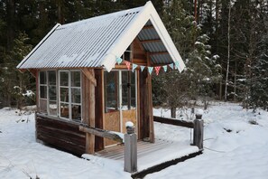 A wooden cabin with a metal roof, surrounded by snow-covered trees.