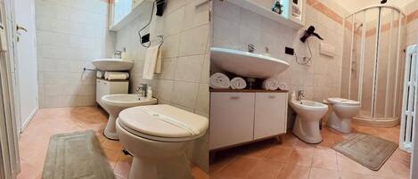 Un baño con dos inodoros, un bidé, un lavamanos y una cabina de ducha.