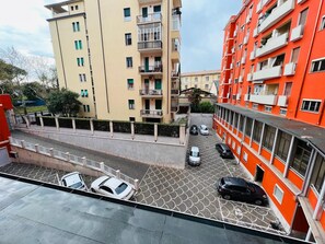 Ein Wohngebäude mit mehreren Balkonen und einem Parkplatz mit Autos.