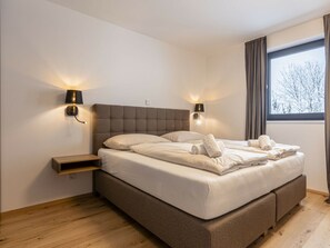 A modern bedroom with a large bed, two bedside lamps, a nightstand, and a window with curtains. - Holiday Apartment for 6 People & Infinity Pool (Sankt Martin am Tennengebirge)