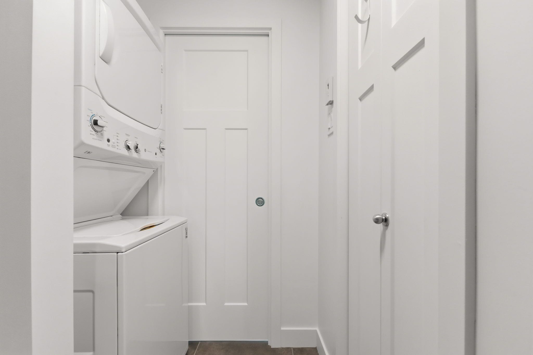 A laundry room with a washing machine, a dryer, and a door.