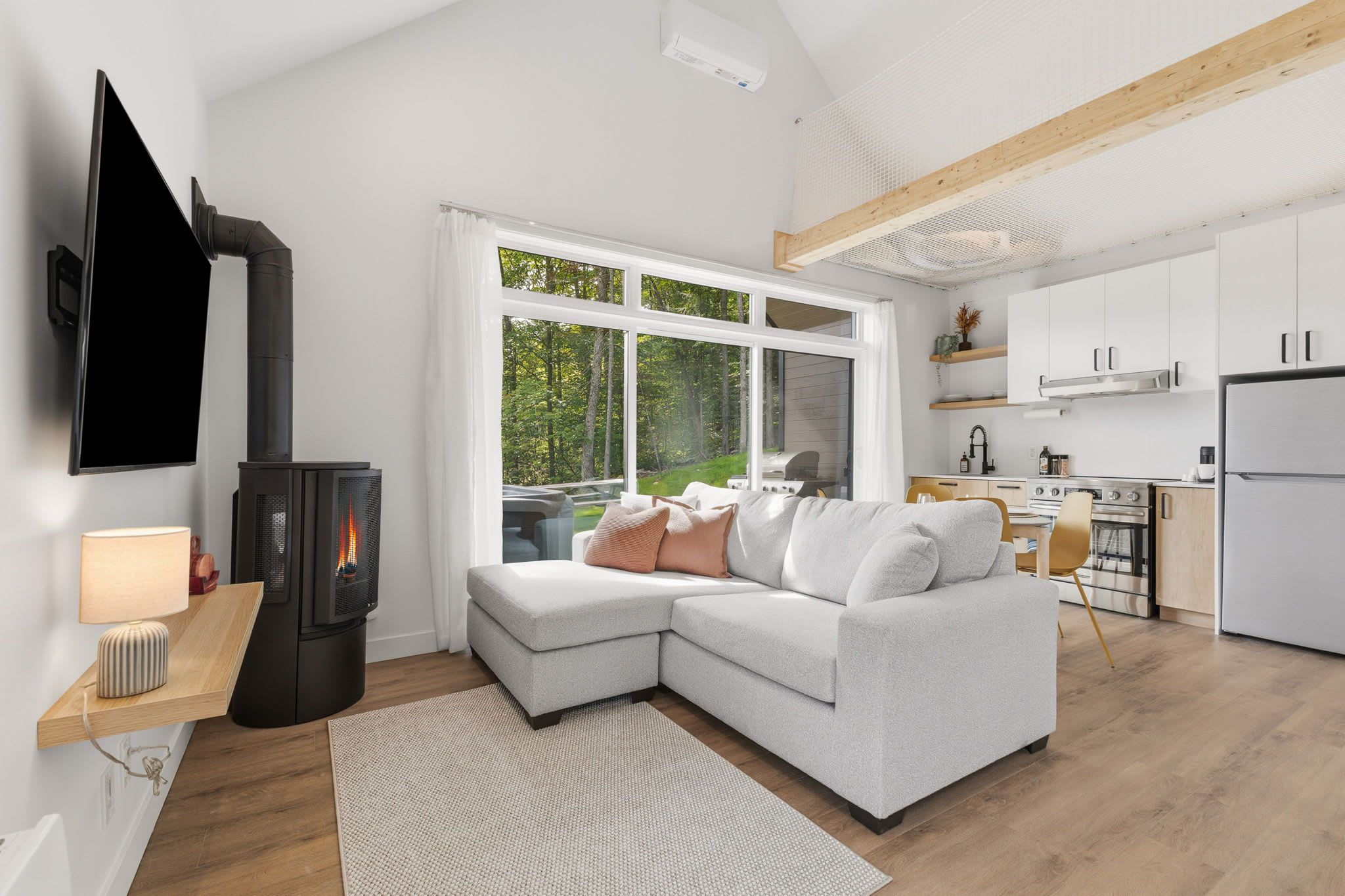 Ein modernes Wohnzimmer mit einer Eckcouch, einem Kamin und einer Küchenzeile mit weißen Schränken und Geräten.