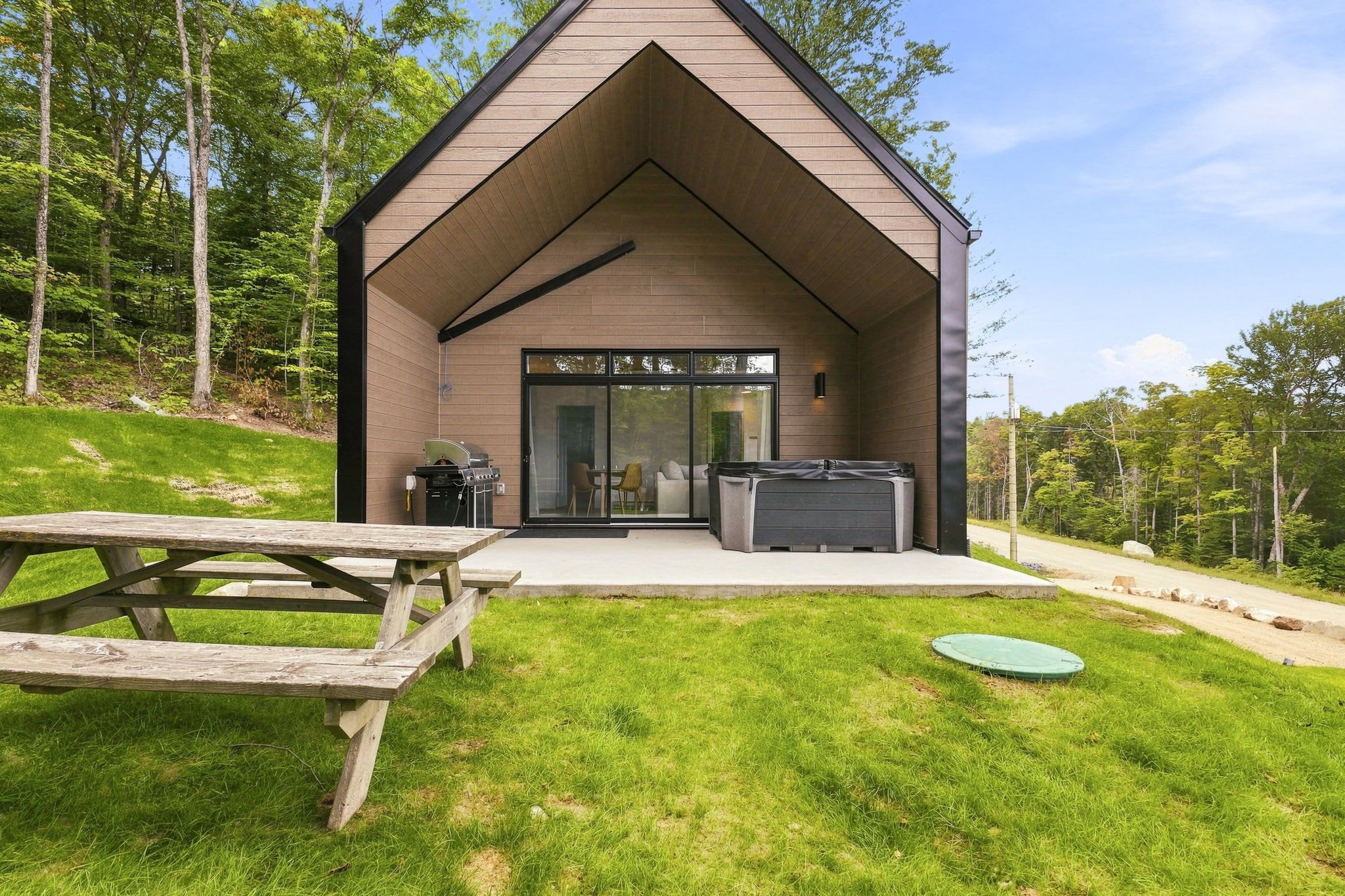 A modern building with a sloped roof, a patio area with a grill, and a large sliding glass door.