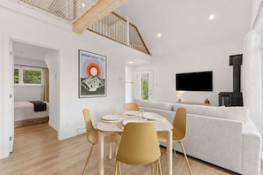 A modern living space with a dining area, a sofa, a TV, and a fireplace. - Spa & Nature in Saint-Come - Oslo-40 (Saint-Côme)