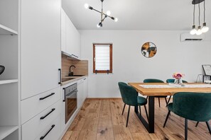 Une cuisine moderne avec des meubles blancs, une table à manger en bois et des chaises vertes.