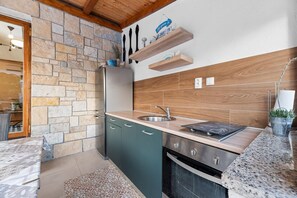 Une cuisine compacte avec un mur en pierre, un plan de travail en bois et un four encastré.